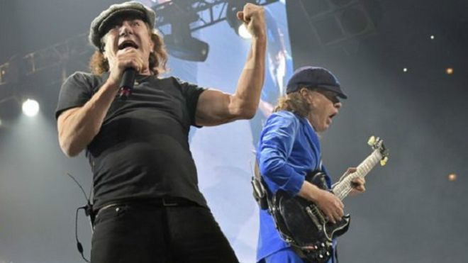 برايان جونسون (إلى اليسار) عرف بارتدائه الكاب التي صارت علامة مميزة له